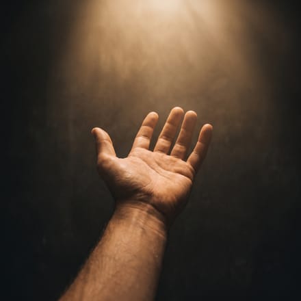 An open hand reaching toward warm golden light.