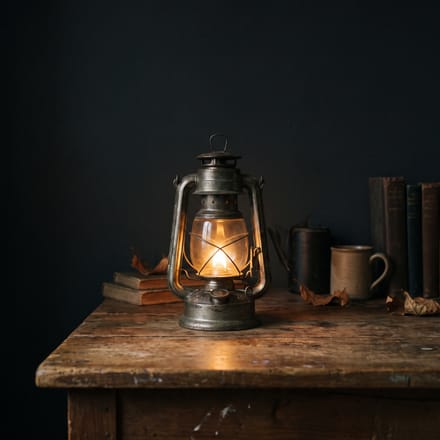 A warm glowing lantern on a wooden table in a dark room.