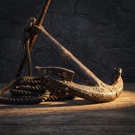 A rusted iron ship's anchor with rope, lit warm gold.